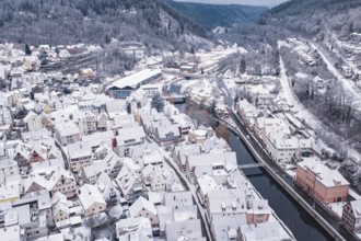 City in winter with snowy buildings, river and adjacent hills and bridge, Calw, Black Forest,