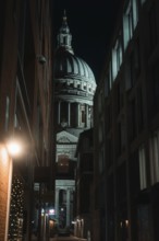 Illuminated St Paul Cathedral through narrow alley at dusk, historic backdrop, London, England,