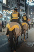 Mounted police at night on a street with festive lights, London, England, Great Britain