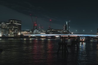 River landscape with night lighting and visible cranes, London, England, Great Britain