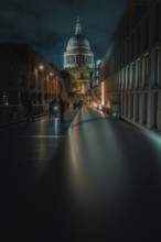Illuminated bridge with St Paul Cathedral and city background at night, people walking, London,