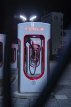Tesla charging station illuminated at night with eye-catching red in a modern design, Tesla