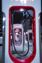 Tesla charging stations at night with red lighting and modern optics, Tesla Supercharger,