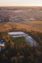 View of a snowy sports field near a town surrounded by trees and countryside, Althengstett, Calw