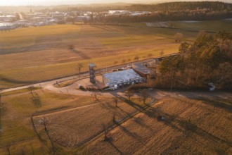 Aerial view of a landscape in evening light with fire station surrounded by fields and trees,