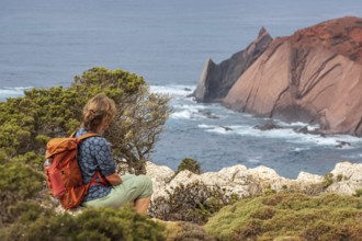 Hiking woman takes a break, view over cliff, Fishermens Trail, Rosa Vicentina, western Algarve just