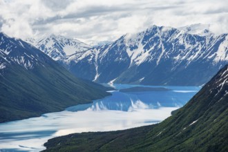 View of snowy mountains in spring and turquoise Kenai Lake with reflection, Slaughter Ridge Trail,