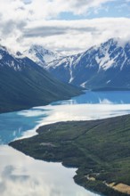 View of snowy mountains in spring and turquoise Kenai Lake with reflection, Slaughter Ridge Trail,