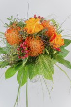 Colorful bouquet in a vase with orange and yellow flowers, red berries and green leaves, protea,