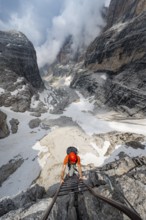 Mountaineer climbs a ladder in steep rocky terrain, Via Ferrata Oliva Detassis via ferrata, view of