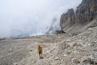 Mountaineers on a hiking trail in a rocky, cloud-covered mountain landscape while descending to