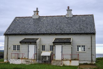 An old grey lighthouse dictionary house with a sloping roof at Kjølnes Fyr, small windows and