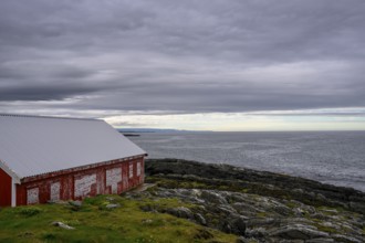A red barn at Kjølnes Fyr, small windows and railings in a rural area, Berlevåg, Finnmark, Norway