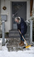 Elderly woman with broom, sweeping week, cleaning, sweeping snow, sidewalk, sidewalk, snowfall,