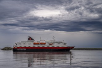 The Hurtigrouten Hurtigruten ship Kong Harald arrives at Berlevag harbour, on the horizon with a