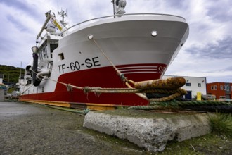 Large fishing boat fishing vessel in harbor secured by thick ropes cords on a massive