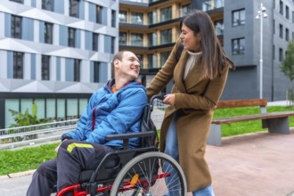 Woman companion assisting a smiling man using a wheelchair, enjoying a happy moment together in an