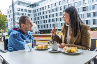 Man with a disability in a wheelchair discussing and smiling with his female social worker over