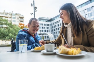 Smiling caregiver offering food to a man in a wheelchair, enjoying a pleasant conversation and meal