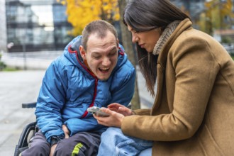 Disabled man in a wheelchair smiling with a female caretaker enjoying a fun moment together while