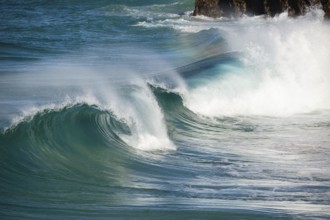 Waves crash against rocks at the mainland's easternmost point, creating rainbows in the ocean spray