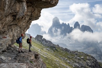Two mountaineers on a path in front of a picturesque mountain landscape with rocky peaks, Via