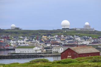 View of the port city of Vardø with large NATO radar systems on a hill in the background, Vardö,