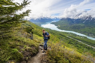 Climbers on a hiking trail, Slaughter Ridge Trail, view of snowy mountains and turquoise lake Kenai