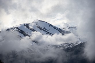 Cloudy snowy mountain peak in spring, Kenai Peninsula, Alaska, USA