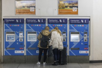 Ticket vending machine at Stuttgart Airport with travelers buying a public transport ticket.