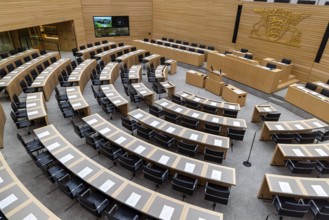 Plenary hall deserted with the seats of deputies and the government bank. Behind it is the coat of
