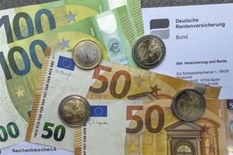 Symbolic photo document pension certificate from Deutsche Rentenversicherung on it cash banknotes