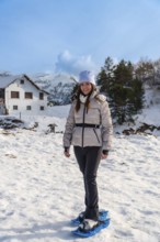 Woman smiling while snowshoeing in the snow, enjoying a winter active holiday in snowy mountains