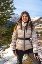 Young woman smiling at camera in snowy mountain landscape, wearing warm jacket and enjoying a