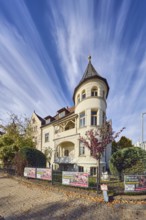 Historic residential buildings, turrets, balcony, façade with windows, trees with autumn leaves,