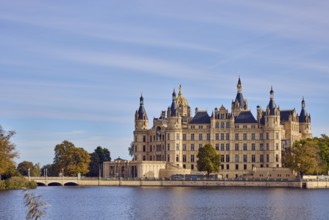 Castle, Burgsee lake, trees, bushes, car bridge and footbridge, water surface with small waves,