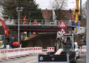 Construction workers with construction machinery on a railway bridge construction site,
