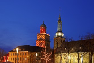 The Christmassy illuminated town hall tower and the illuminated church tower of St. John's Church
