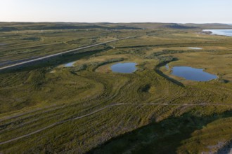 Coastal landscape on Varangerfjord with blue sky, still sea, moors and pebble beach aerial view,
