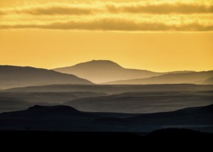 Silhouettes of mountains at sunset with yellow sky, near Vadsö, Finnmark, Norway