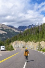 Female tourist walking on the iconic icefields parkway in the canadian rockies, enjoying