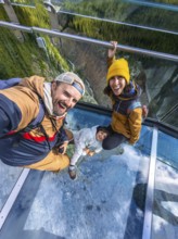 Happy family taking a selfie while standing on the glass floor of the glacier skywalk, enjoying the