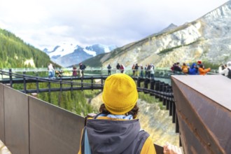 Tourist wearing a yellow beanie stands on a viewing platform, admiring the stunning view of