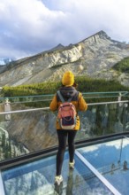 Hiker enjoying breathtaking view of sunwapta valley from glass floor on glacier skywalk at columbia