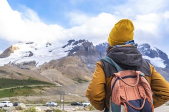Hiker wearing a yellow beanie and carrying a backpack enjoying the breathtaking view of the