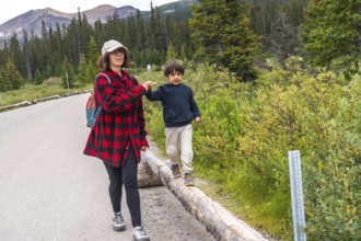 Mother and son enjoying a leisurely walk along a scenic road in banff national park, surrounded by