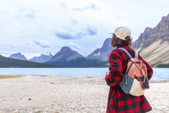 Female tourist with a backpack admiring the breathtaking turquoise waters of bow lake and the