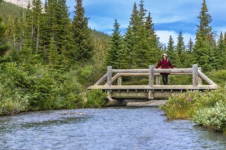 Female hiker enjoying the view from a wooden bridge over a river flowing from bow lake in banff