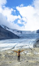 Female hiker with backpack and yellow jacket is enjoying the breathtaking view of the athabasca