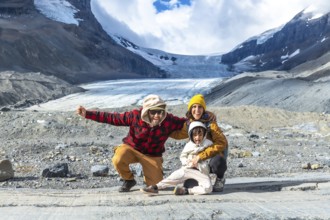 Happy family posing for a photo in front of the breathtaking athabasca glacier in jasper national